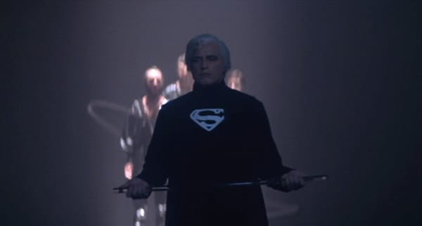 Figure wearing Superman shirt standing with arms spread in dramatic lighting with glowing effects